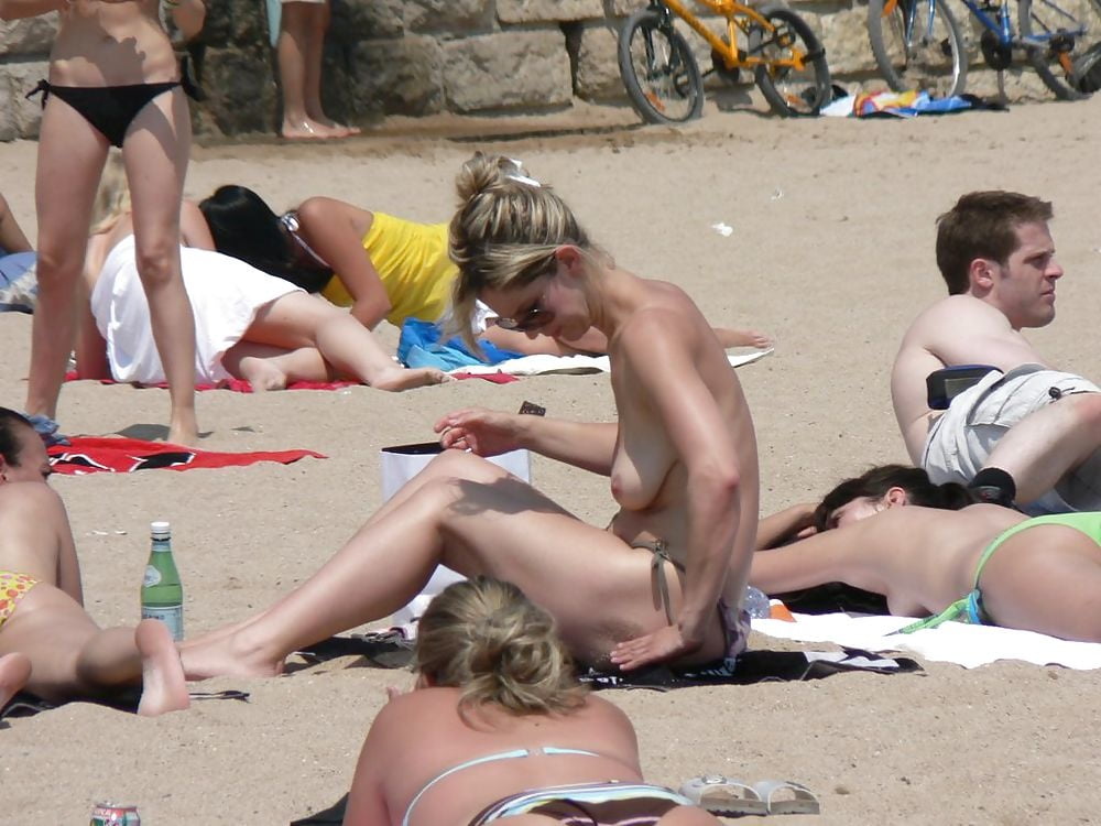 金髪の女性が浜辺で着替えている姿は、トップレスの恋人たちのためのものです。
 #97316206