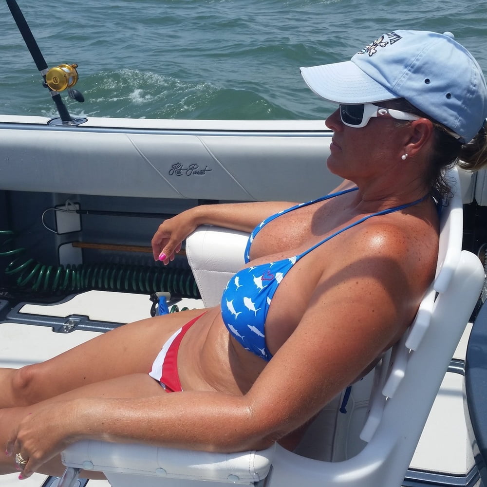 ボートで釣りをしているホットなビキニ姿の女性
 #99094541
