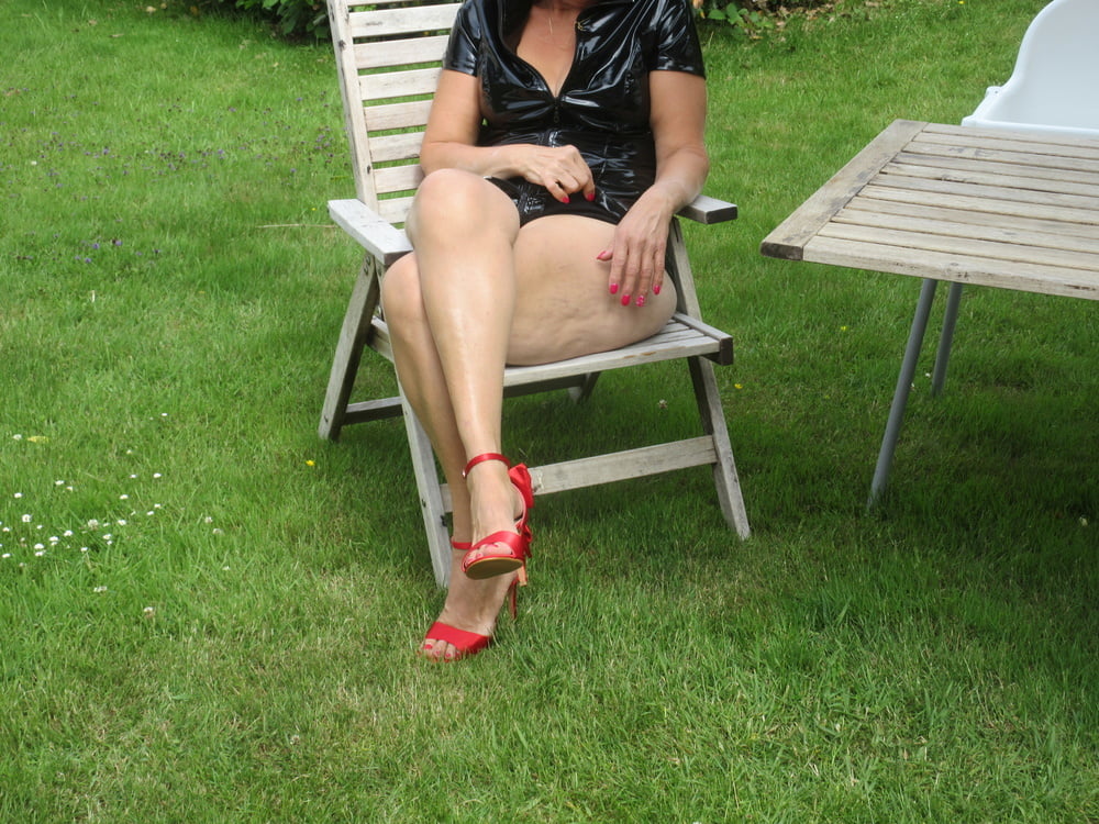 Rote Schuhe mit hohem Absatz, schwarzes Outfit, Upskirt im Garten
 #91401763